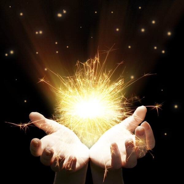 Hands with sparkler light on dark background