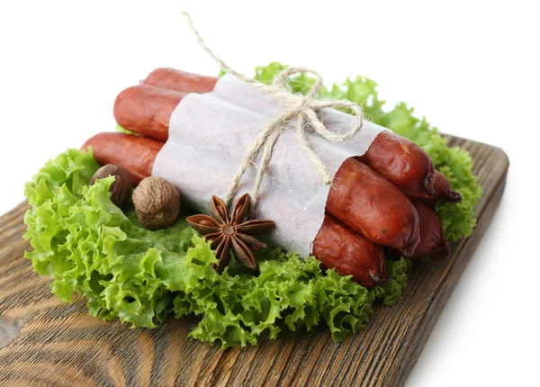 Salsichas finas defumadas com folhas de salada de alface em tábua de corte de madeira, isoladas em branco — Fotografia de Stock