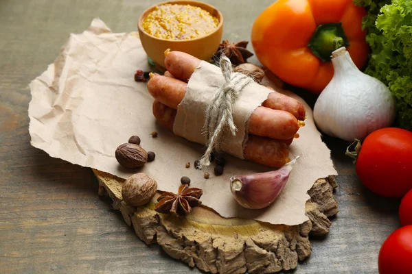 Состав тонких колбас, горчицы в миске и специй на деревянном фоне — стоковое фото