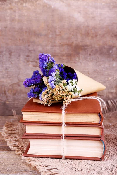Libros y flores silvestres en servilleta sobre mesa de madera sobre fondo de pared de madera — Foto de Stock