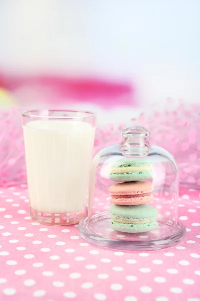 Macarrones coloridos suaves y vaso de leche sobre fondo brillante — Foto de Stock