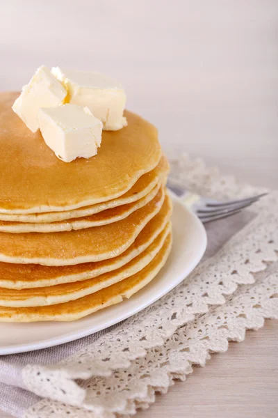 Pilha de deliciosas panquecas com manteiga na mesa e fundo leve — Fotografia de Stock