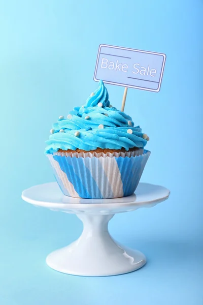 Delicious cupcake with inscription on blue background — Stock Photo, Image