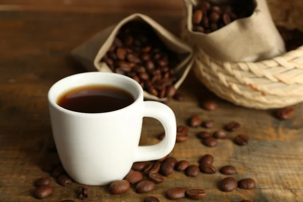 Tasse Kaffee mit Bohnen auf rustikalem Holzgrund — Stockfoto