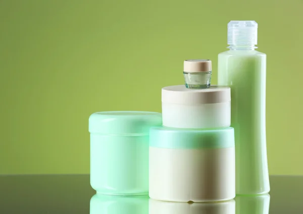 Cosmetic bottles on light green background — Stock Photo, Image