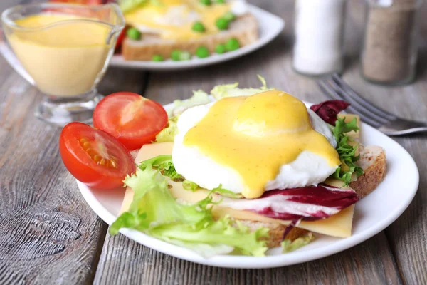 Toast med ägg Benedict och tomat på plattan på träbord — Stockfoto