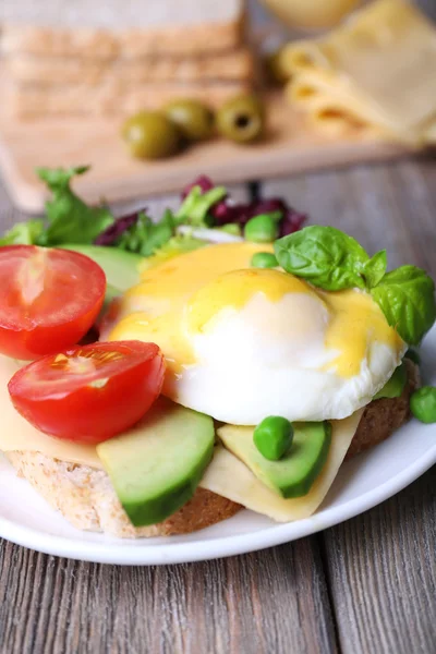Toast with egg Benedict and avocado on plate on wooden table — Stock Photo, Image