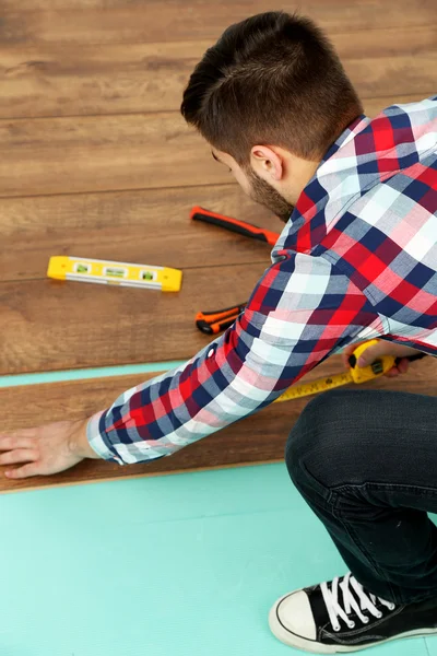 Trabajador carpintero instalación de pisos laminados en la habitación —  Fotos de Stock