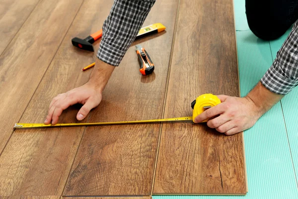 Timmerman installeert laminaat vloeren in de kamer — Stockfoto