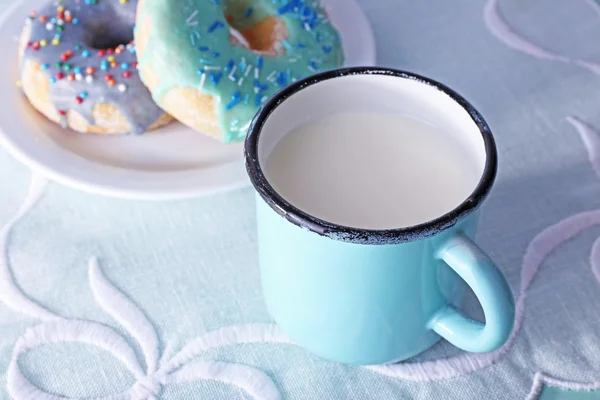 Glaserade donuts med kopp mjölk på vit servett bakgrund — Stockfoto