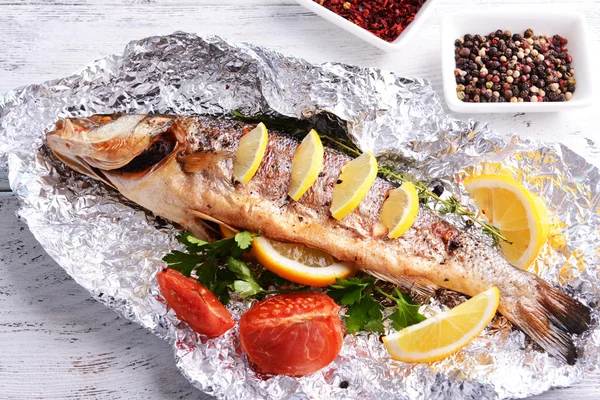 Tasty baked fish in foil on table close-up — Stock Photo, Image