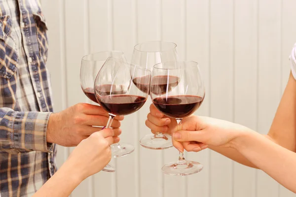 Clinking copos de vinho tinto em mãos em pranchas de madeira cor de fundo — Fotografia de Stock