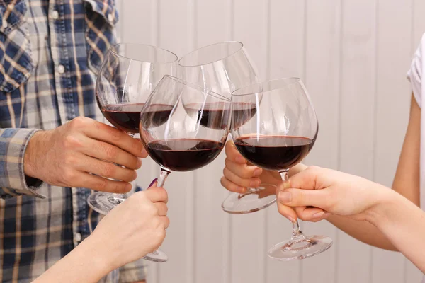 Copas de vino tinto en las manos sobre tablones de madera de color de fondo —  Fotos de Stock