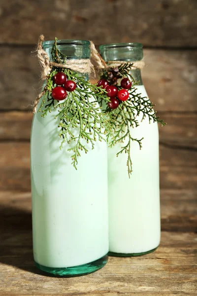 Flessen van verse melk met natuurlijke decor, op houten achtergrond — Stockfoto