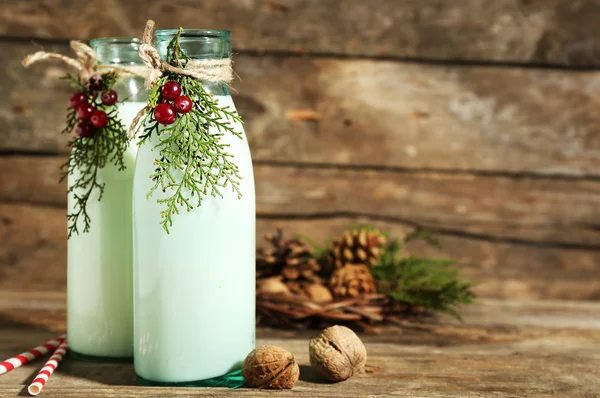 Botellas de leche fresca con decoración natural, sobre fondo de madera —  Fotos de Stock