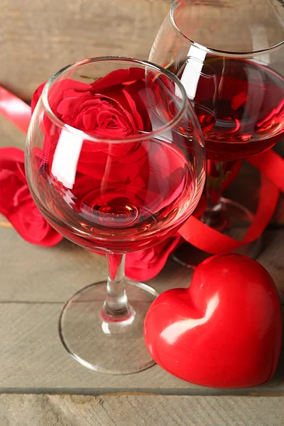 Composición con vino tinto en copas, rosas rojas y corazón decorativo sobre fondo de madera —  Fotos de Stock