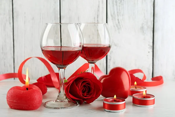 Composizione con vino rosso in vetro, rose rosse e cuore decorativo su sfondo di legno a colori — Foto Stock