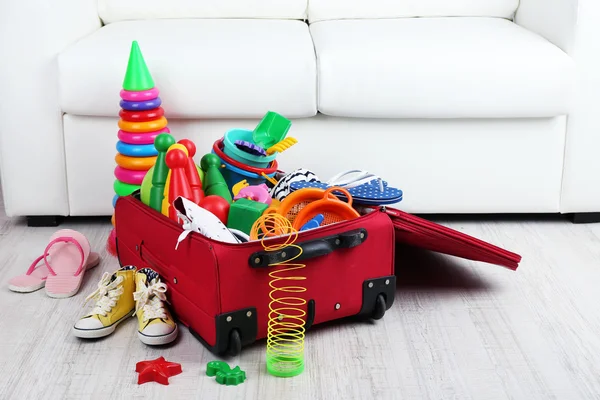 手提箱里装好衣服和儿童玩具木地板和白色的沙发背景 — 图库照片