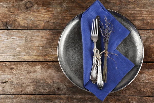 Silverware tied with rope on metal tray with colorful napkin and dried flower on wooden planks background — Stock Photo, Image