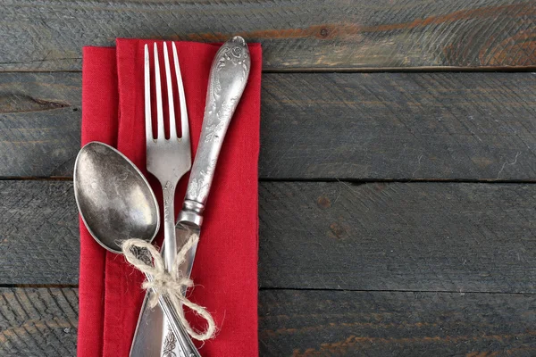 Silberbesteck gebunden mit Seil auf bunte Serviette und Holzplanken Hintergrund — Stockfoto