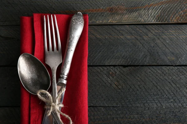 Silberbesteck gebunden mit Seil auf bunte Serviette und Holzplanken Hintergrund — Stockfoto