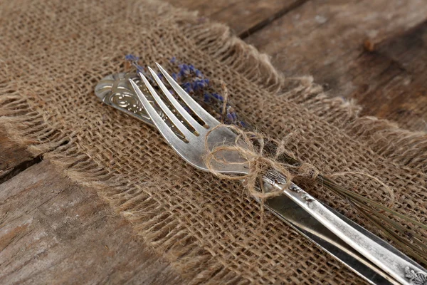 Zilverwerk vastgebonden met touw jute doek en rustieke houten planken achtergrond — Stockfoto