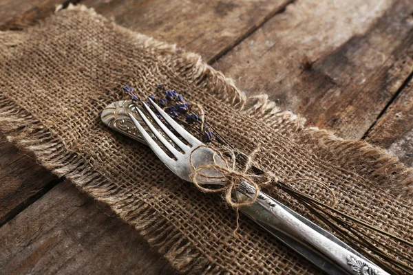 銀器は結んでロープ黄麻布、素朴な木製の板の背景 — ストック写真