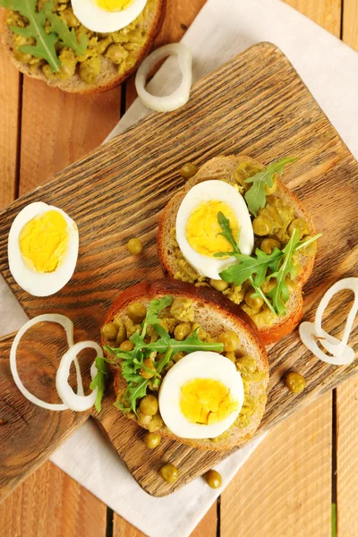 Kanapki z zielonego groszku pasty i jajko na twardo na deska do krojenia z serwetka na tle desek — Zdjęcie stockowe
