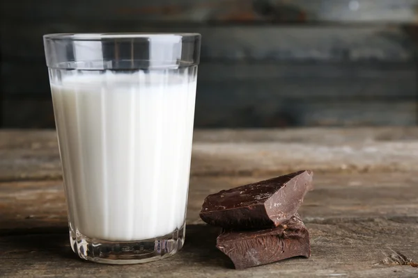 Glass of milk with chocolate chunks on rustic wooden planks background — Stock Photo, Image
