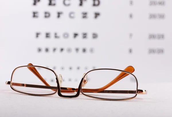 Gafas oculares en el fondo de la tabla de prueba de la vista —  Fotos de Stock