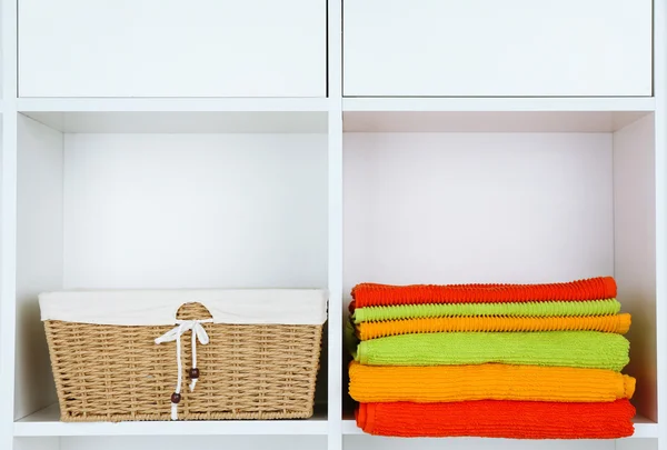 Kolorowe ręczniki z wiklinowym koszu na półce w szafie tła — Zdjęcie stockowe