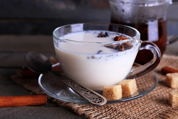 Tè nero con latte in vetreria e zucchero grumo su sfondo tavole di legno colore — Foto Stock