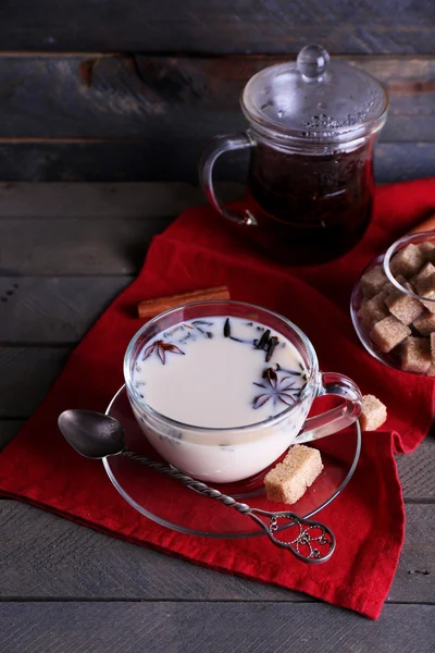 Black tea with milk and lump sugar in glassware on color wooden planks background — Stock Photo, Image