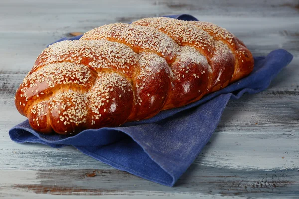 Laib frisches Brot mit Serviette auf farbigem Holztischhintergrund — Stockfoto