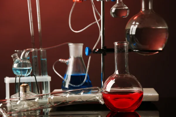 Vaste laboratoriumglaswerk op steun op donkere kleurrijke achtergrond — Stockfoto