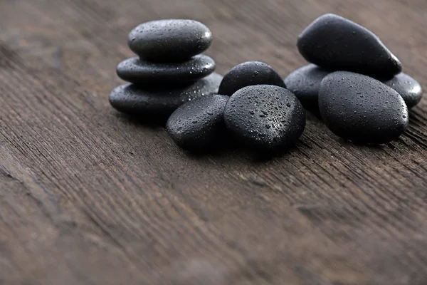 Stack of black sea paddles on rustic wooden background — Stock Photo, Image