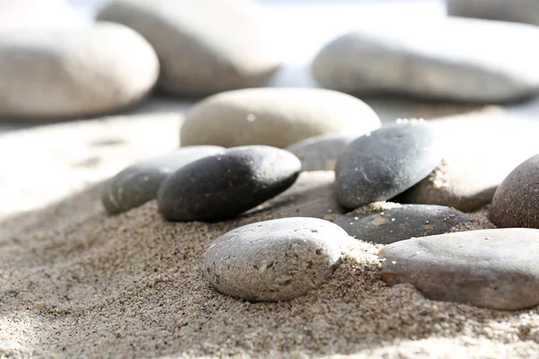 Gray sea pebbles on sand background — Stock Photo, Image