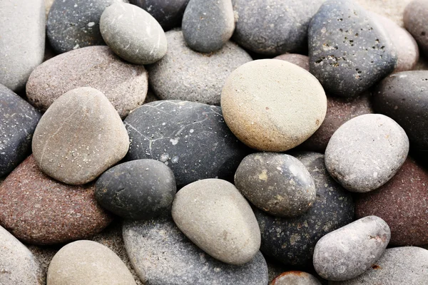 Gray sea pebbles on sand background — Stock Photo, Image