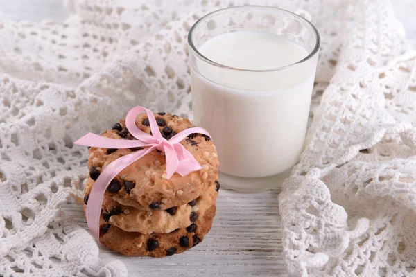 Biscoitos saborosos e vidro de leite na cor de fundo de madeira — Fotografia de Stock