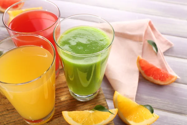 Färska juicer med frukter på träbord — Stockfoto