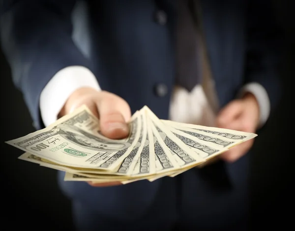 Επιχειρηματίας δίνει χρήματα σε σκούρο φόντο — Φωτογραφία Αρχείου