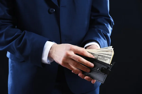 Bőr pénztárca, pénzzel, a férfi keze a sötét háttér — Stock Fotó