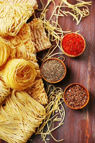 Different dry instant noodles with spices on wooden background — Stock Photo, Image