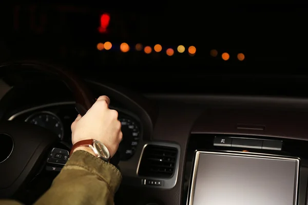 Чоловік керує своєю сучасною машиною вночі в місті, крупним планом — стокове фото