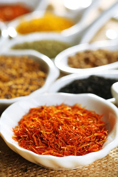 Different kinds of spices in ceramics spoons, close-up, on sackcloth background — Stock Photo, Image