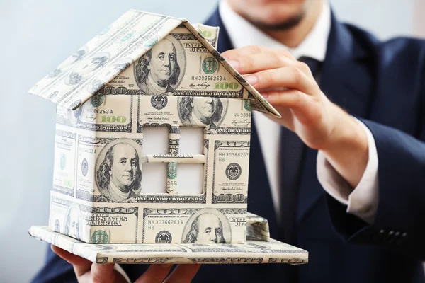 Model of house made of money in male hands on white background — Stock Photo, Image