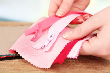 Renkli kumaş örnekleri ve hafif bulanık arka plan üzerinde eller içinde fermuar