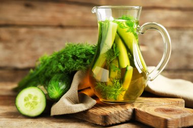 Ahşap masa üzerinde taze organik salatalık suyu ile cam ibrik