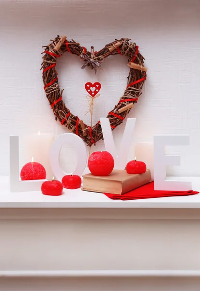 Hasır kalp ve mum ile romantik natürmort şöminenin ve beyaz duvar arka plan üzerinde ışıklar — Stok fotoğraf