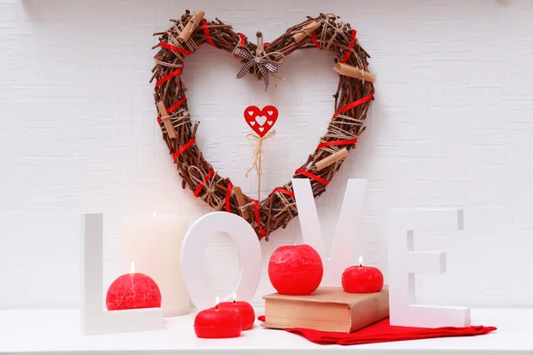Bodegón romántico con corazón de mimbre y luces de vela en repisa de chimenea y fondo de pared blanco —  Fotos de Stock